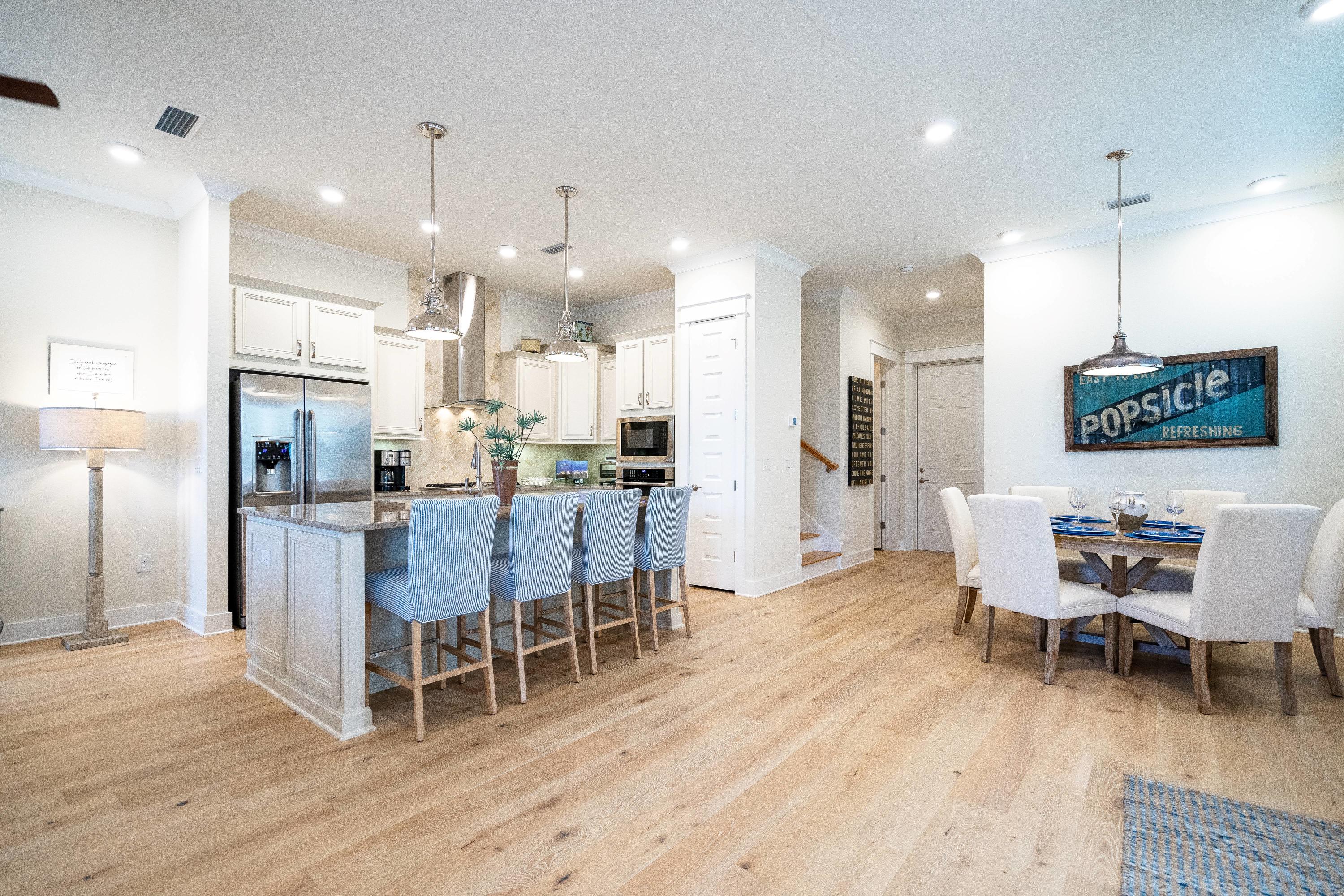 89 East Pine Lands Loop, Unit A Inlet Beach, FL 32461 - Photo 2 of 41 a dining room with stainless steel appliances kitchen island granite countertop a table chairs and a refrigerator