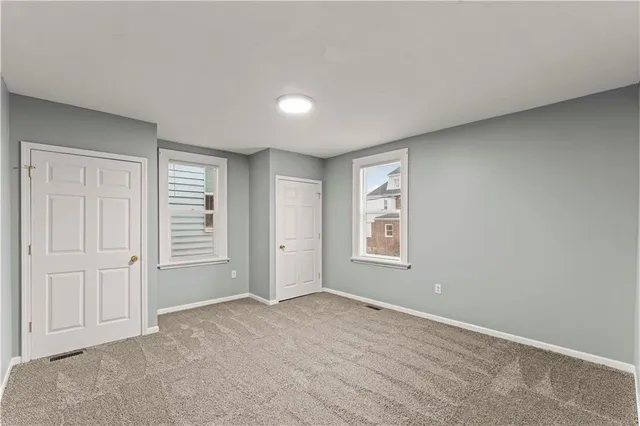 a view of an empty room with closet and a window