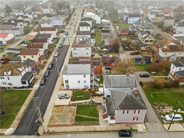 an aerial view of residential houses with outdoor space and parking