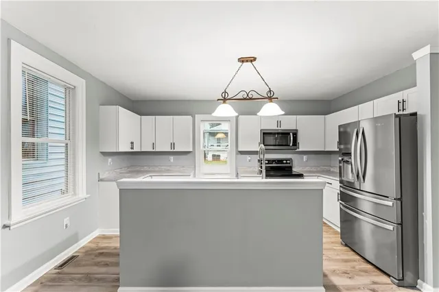 a kitchen with stainless steel appliances granite countertop a sink dishwasher a refrigerator a stove top oven a counter space and cabinets