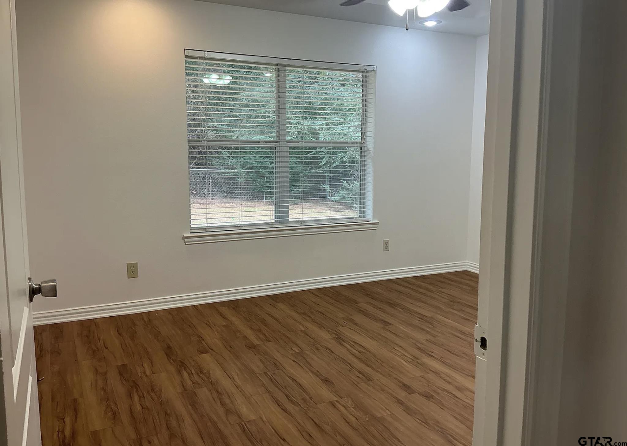 303 Kenneth Street Chandler, TX 75758 - Photo 24 of 33 an empty room with wooden floor and windows