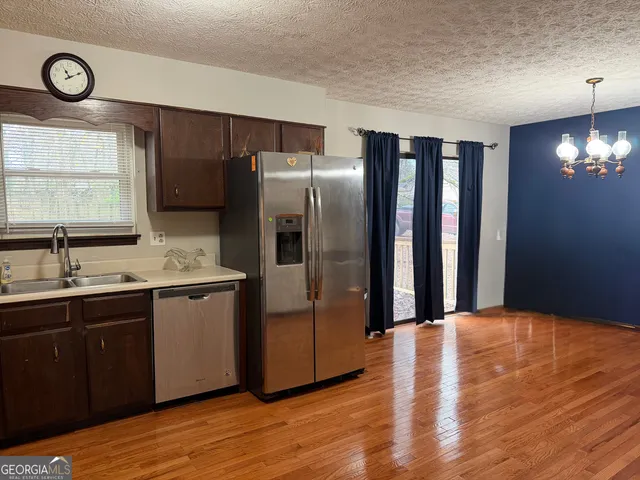 a kitchen with stainless steel appliances granite countertop a refrigerator a sink a stove and island with wooden floor