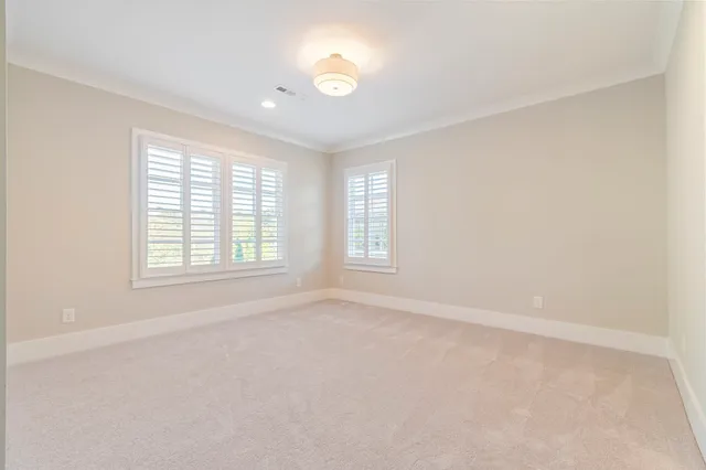an empty room with chandelier fan and windows