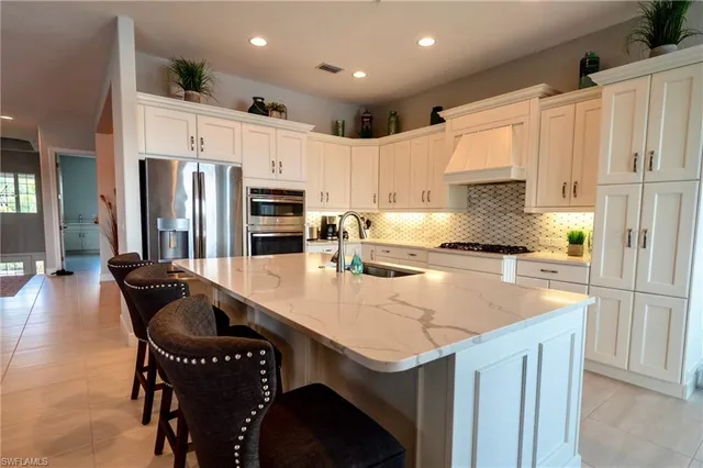 a kitchen with granite countertop kitchen island a table and a refrigerator
