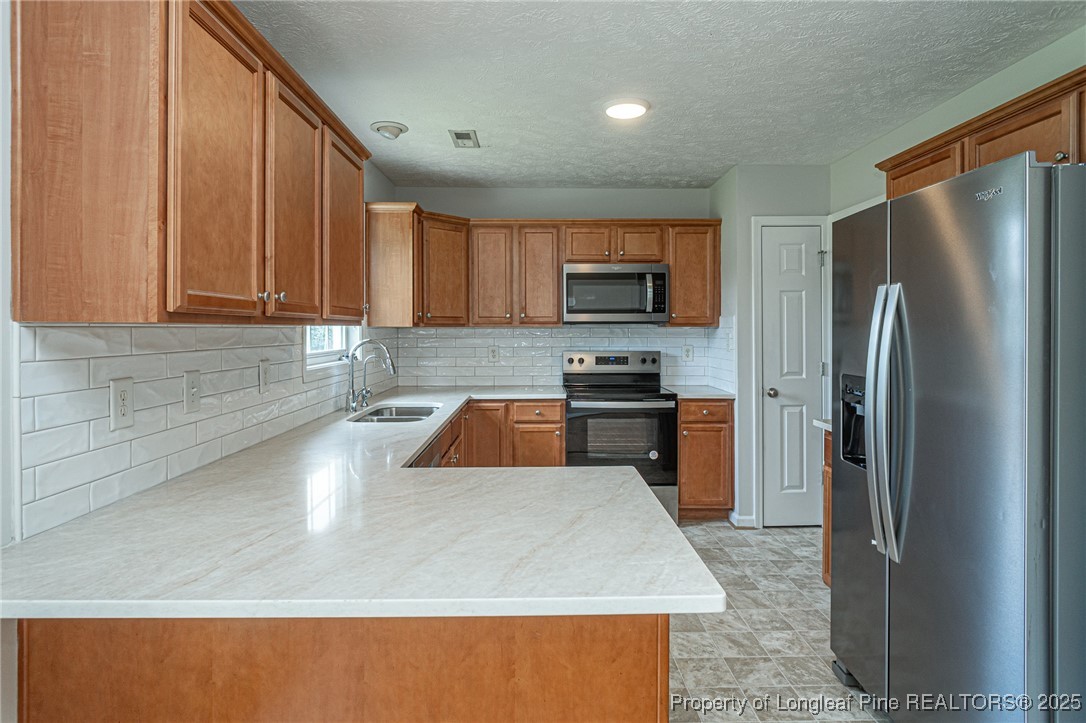 7650 Rufus Johnson Road Fayetteville, NC 28306 - Photo 11 of 43 a kitchen with stainless steel appliances granite countertop a refrigerator a stove and a sink with wooden cabinets