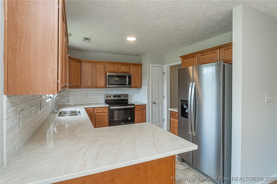 7650 Rufus Johnson Road Fayetteville, NC 28306 - Photo 16 of 43 a kitchen with granite countertop a refrigerator and a sink