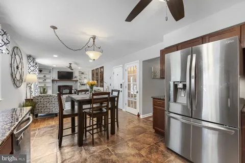 a kitchen with stainless steel appliances a refrigerator a stove a dining table and chairs with wooden floor