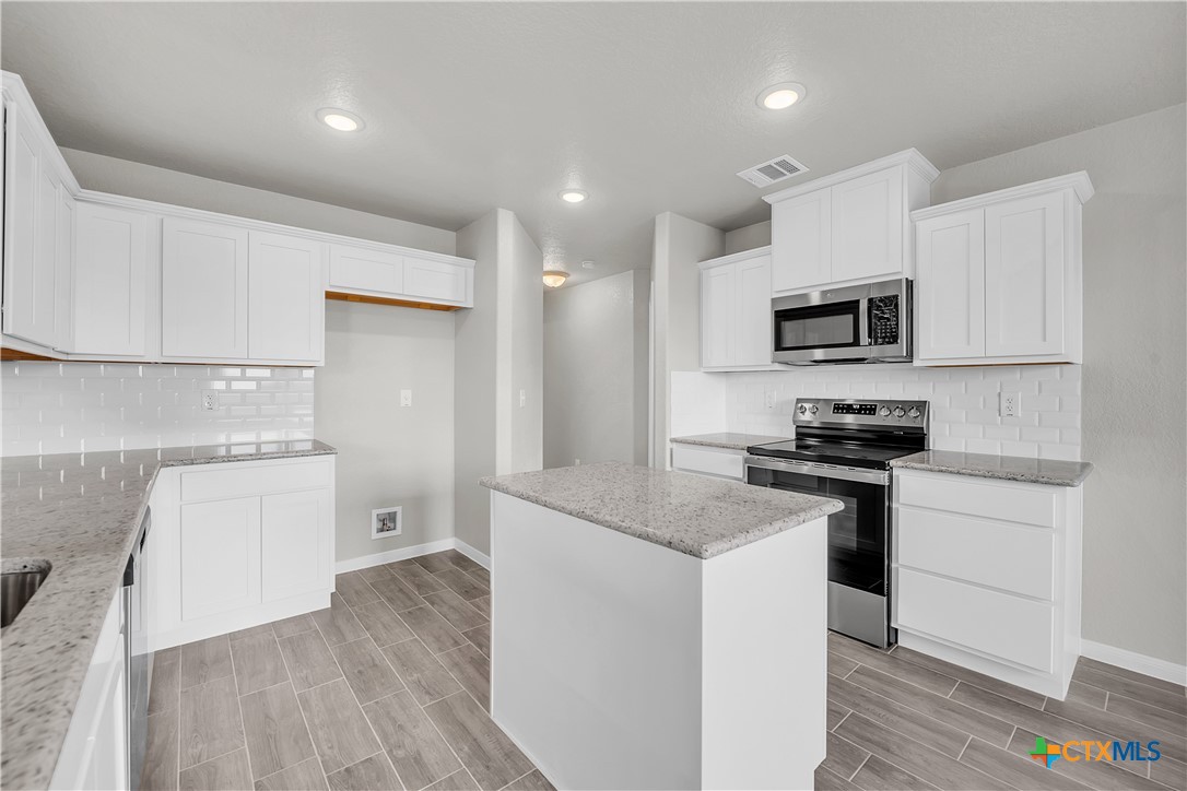 215 Overlook Trail Copperas Cove, TX 76522 - Photo 15 of 36 a kitchen with granite countertop a stove top oven a sink dishwasher and a refrigerator with wooden floor