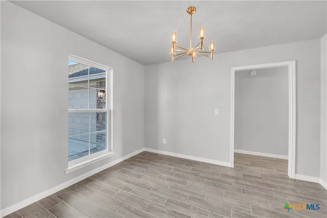 an empty room with wooden floor a fireplace and windows