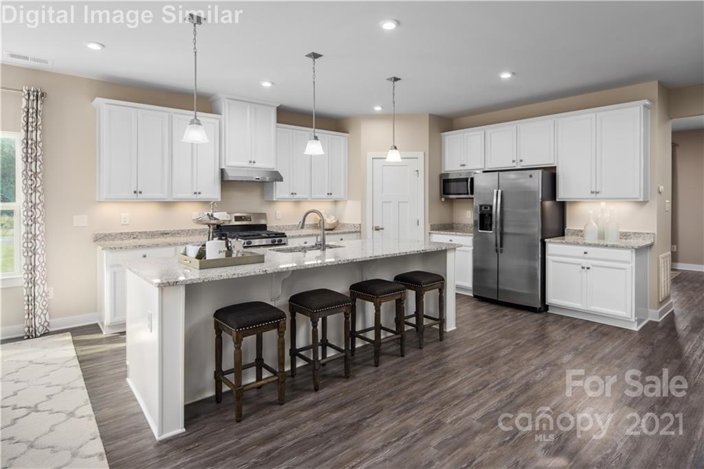 7230 Waterwheel Street Southwest, Unit 100 Concord, NC 28025 - Photo 2 of 23 a kitchen with refrigerator cabinets and wooden floor