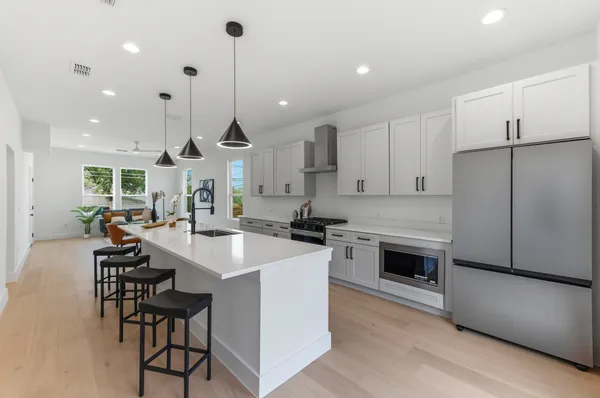a large kitchen with kitchen island a stove a table a chairs and a refrigerator