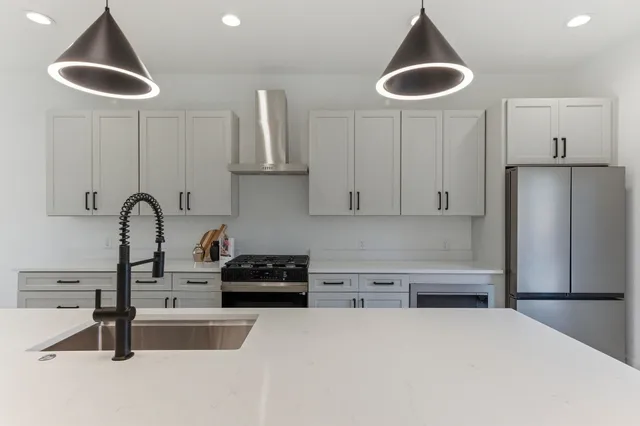 a kitchen with stainless steel appliances granite countertop a sink a stove and a refrigerator