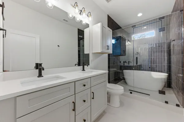 a spacious bathroom with a double vanity sink toilet mirror and bathtub