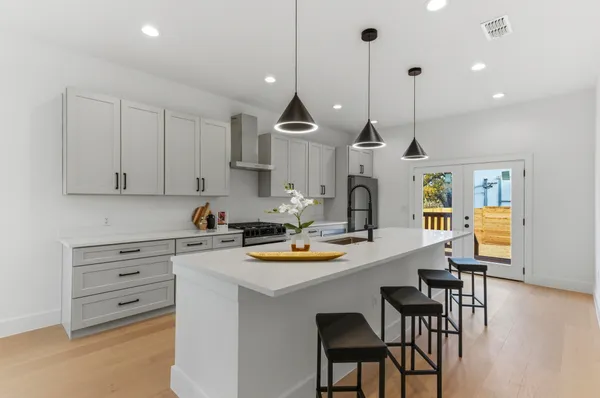a kitchen with stainless steel appliances kitchen island a table chairs and a refrigerator