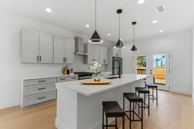 a kitchen with stainless steel appliances kitchen island a table chairs and a refrigerator