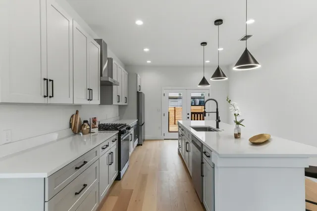 a kitchen with stainless steel appliances a sink a stove and a wooden floors