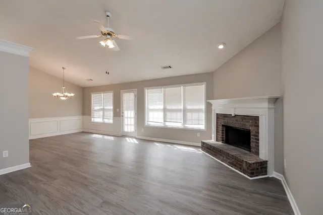 an empty room with wooden floor fireplace and windows