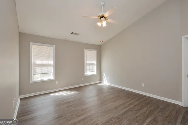 an empty room with wooden floor and window
