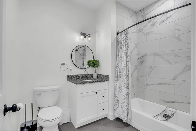 a bathroom with a granite countertop sink a toilet and bathtub