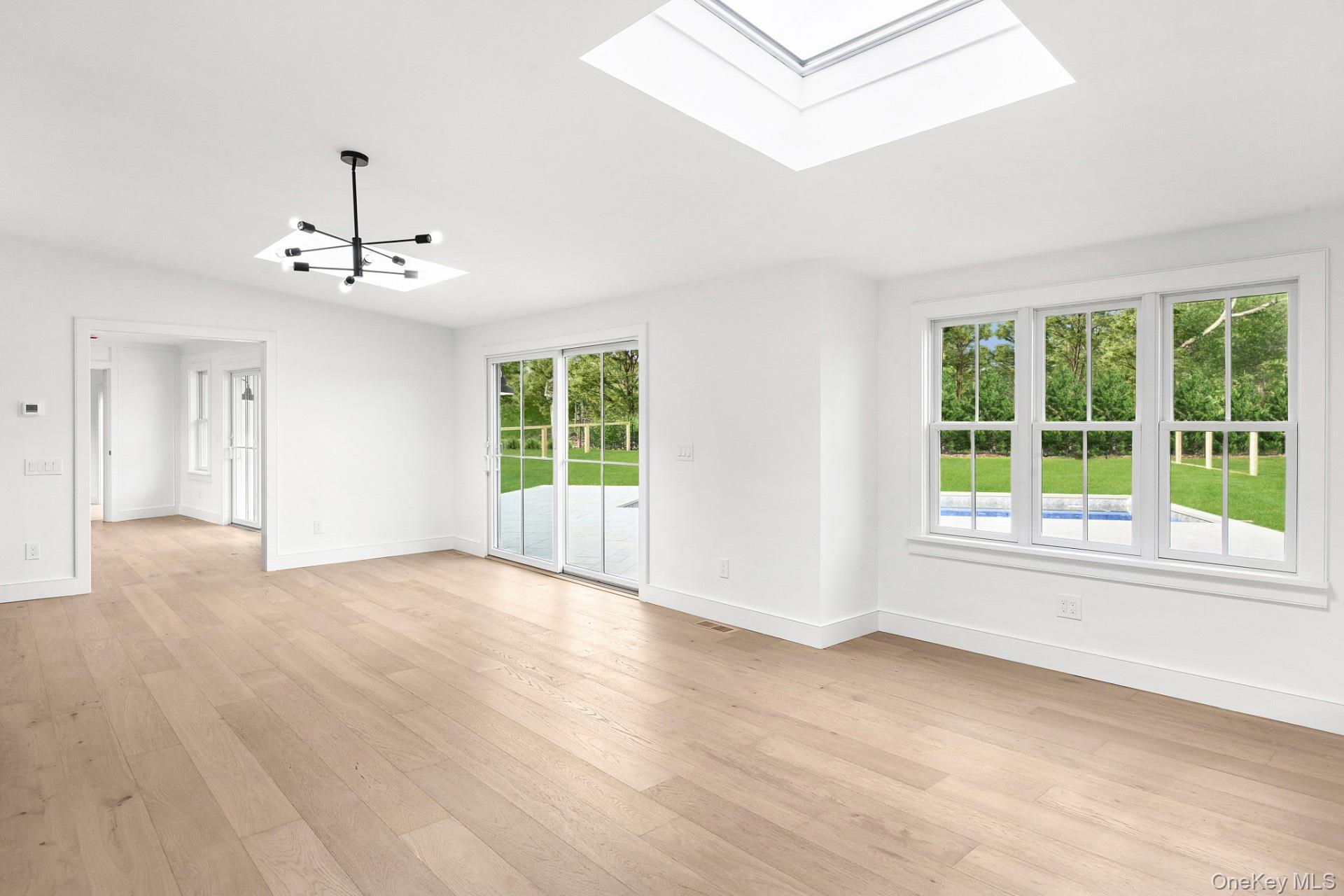 5 Pheasant Lane Remsenburg, NY 11960 - Photo 11 of 27 Spare room featuring light wood finished floors, a skylight, and a chandelier