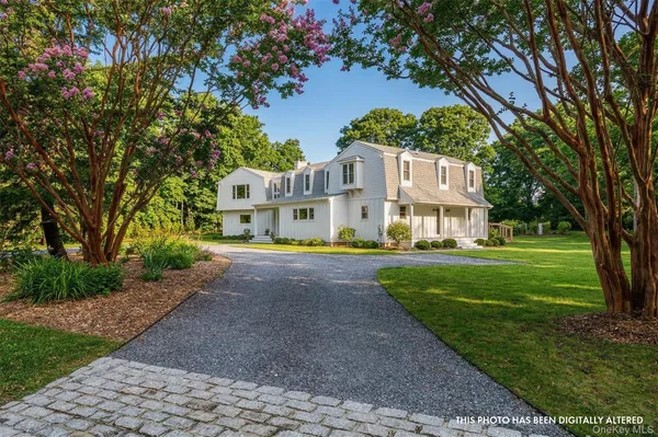 a view of a white house with a big yard and large trees