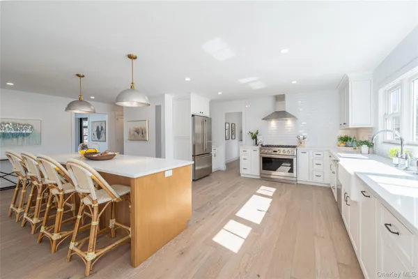 a large kitchen with kitchen island a stove a sink dishwasher and a fireplace with wooden floor