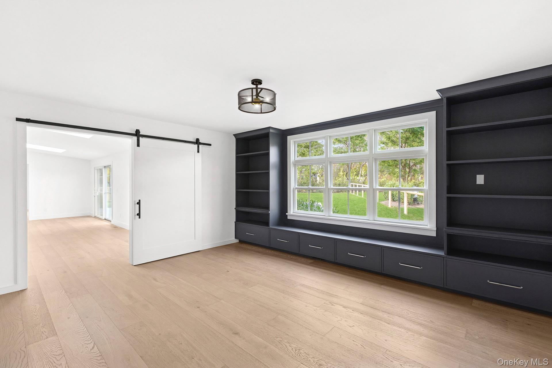 5 Pheasant Lane Remsenburg, NY 11960 - Photo 9 of 27 Unfurnished living room featuring a barn door and light wood-style flooring
