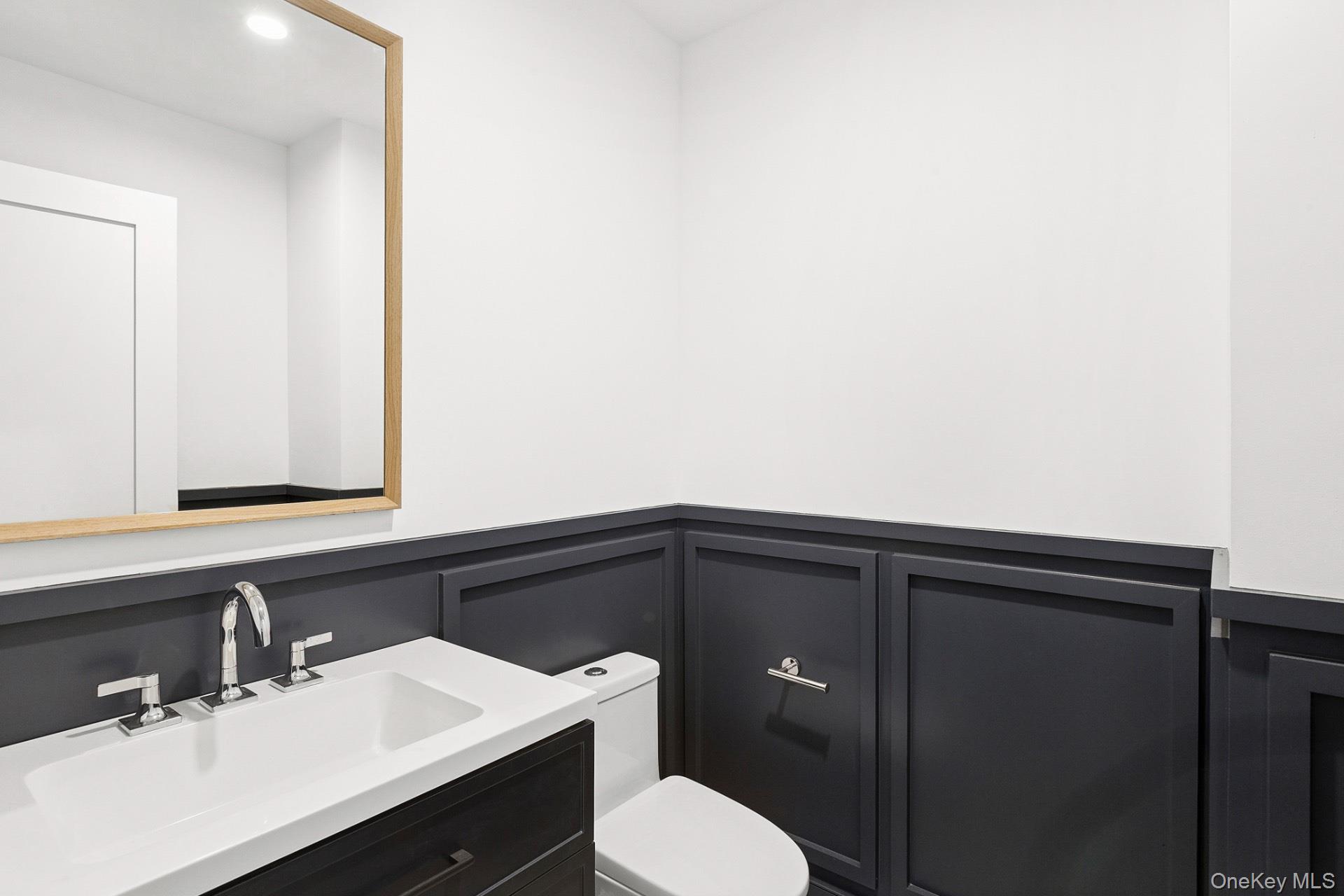 5 Pheasant Lane Remsenburg, NY 11960 - Photo 10 of 27 Half bath with vanity, a decorative wall, and a wainscoted wall