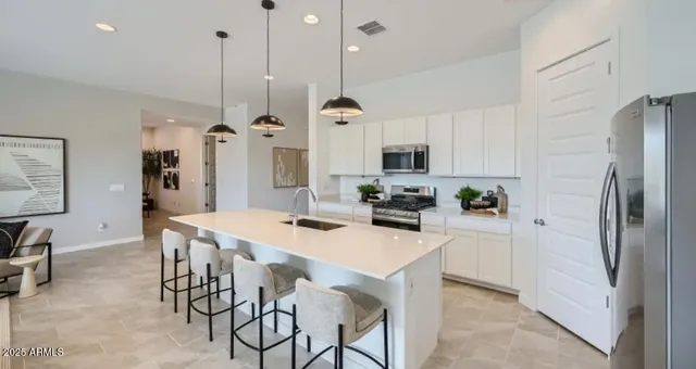 a kitchen with stainless steel appliances granite countertop a refrigerator a sink dishwasher a stove a kitchen island with a dining table and chairs