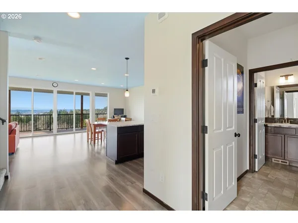 a open hall with stainless steel appliances granite countertop a refrigerator and a wooden floor