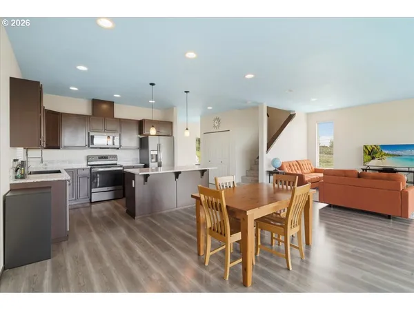a kitchen with stainless steel appliances kitchen island granite countertop a table chairs and a refrigerator