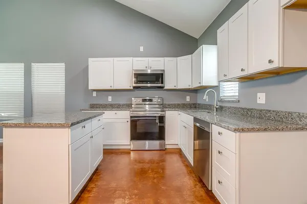 a kitchen with granite countertop a sink stove and cabinets
