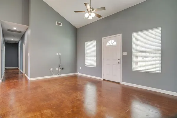 an empty room with wooden floor and windows