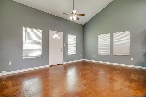 an empty room with wooden floor chandelier and windows