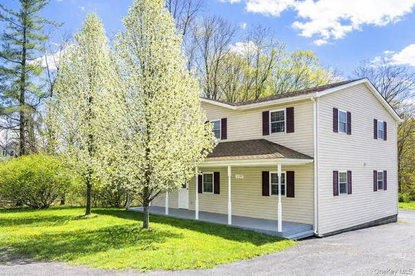 a view of a white house next to a yard with big trees