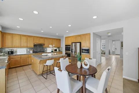 a kitchen with granite countertop kitchen island stainless steel appliances a stove a sink a refrigerator cabinets and dining table