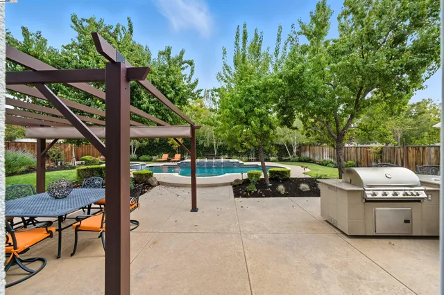 a backyard of a house with table and chairs under an umbrella