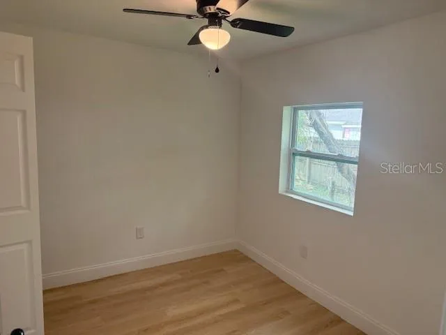 an empty room with a window and a fan