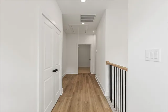 a view of a hallway with wooden floor and a bathroom