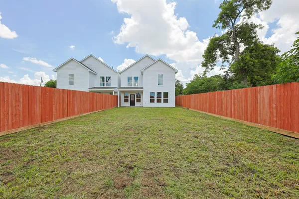 a view of a white house in front of a yard with wooden fence