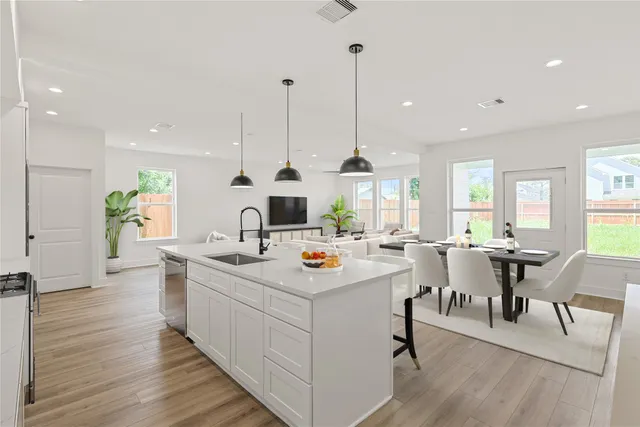 a view of a kitchen with kitchen island stainless steel appliances a table and chairs in it
