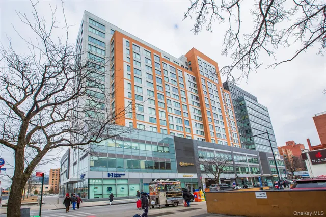 a front view of a building with lot of cars and trees