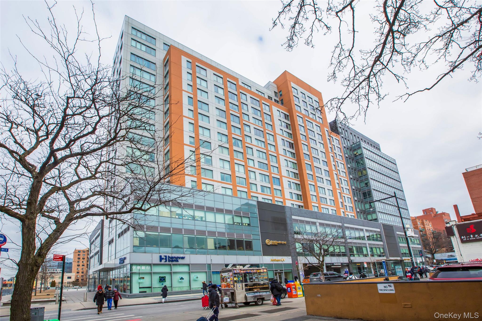 a front view of a building with lot of cars and trees