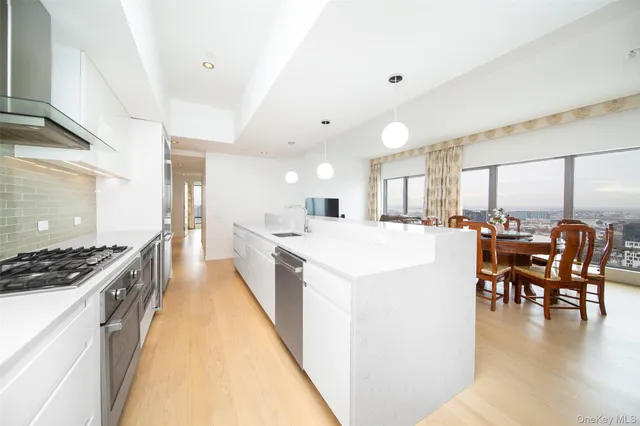 a large white kitchen with lots of counter space a sink a dining table and chairs