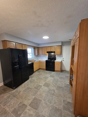 a view of kitchen with refrigerator cabinets and furniture