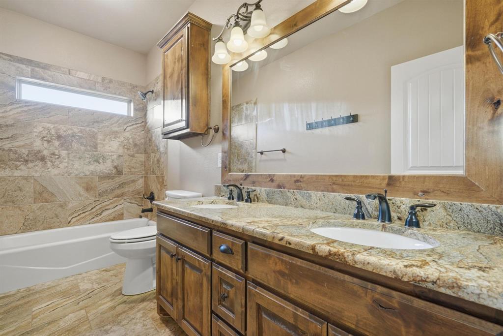 109 Benton Tuscola, TX 79562 - Photo 23 of 40 a bathroom with a granite countertop sink a toilet a mirror and bathtub