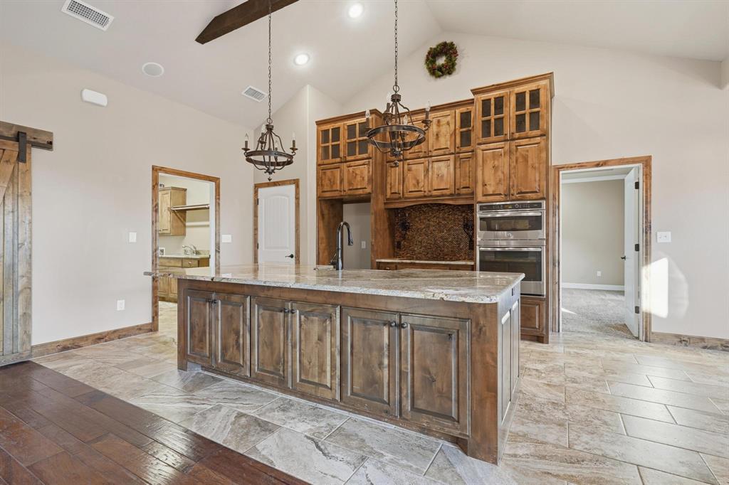 109 Benton Tuscola, TX 79562 - Photo 9 of 40 a kitchen with stainless steel appliances kitchen island granite countertop a refrigerator a stove and oven with wooden floors