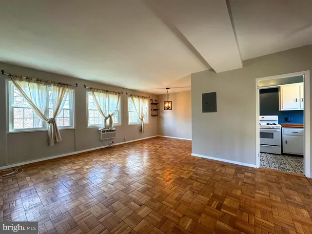 a view of an empty room with a window and wooden floor