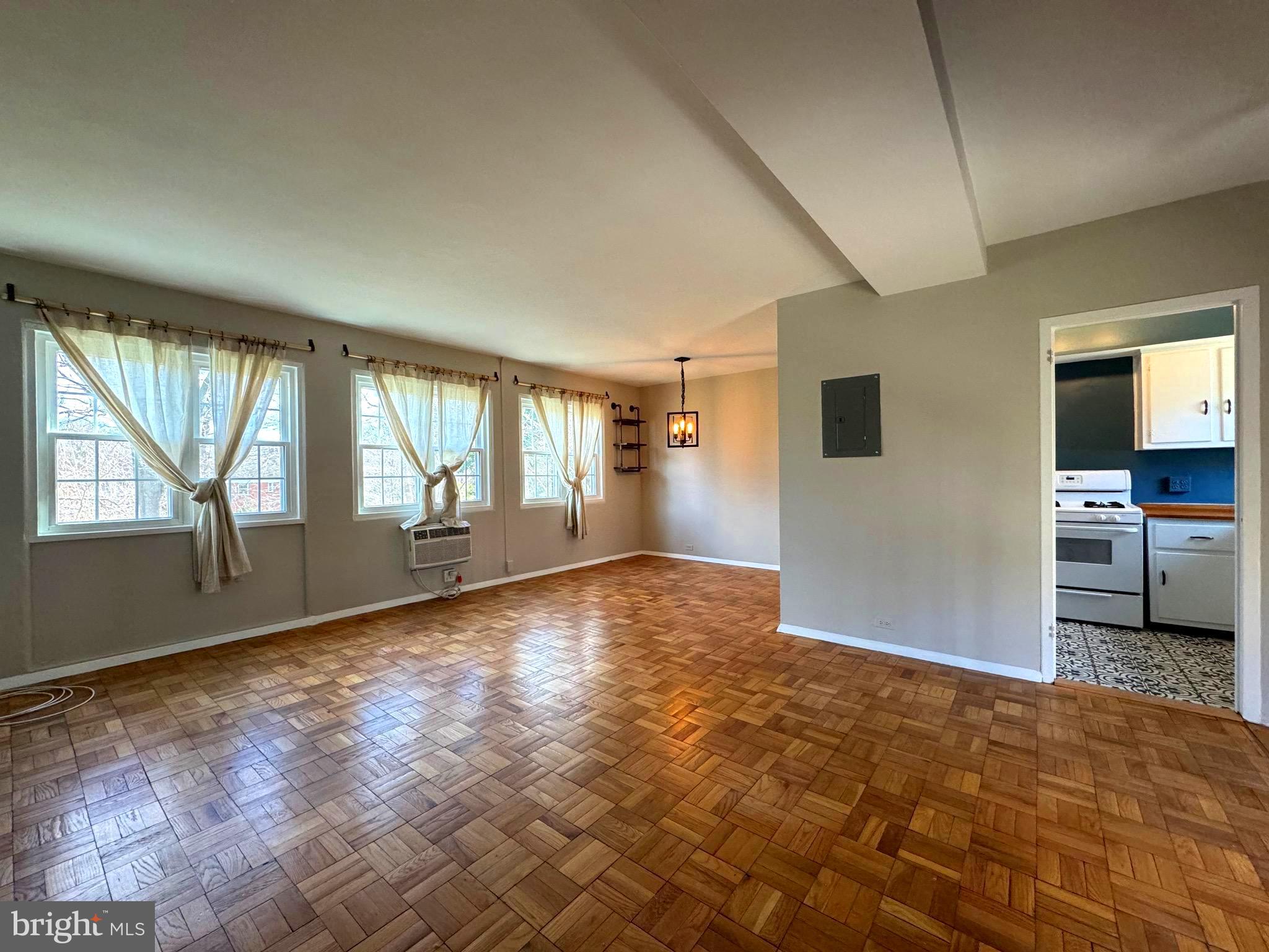 a view of an empty room with a window and wooden floor