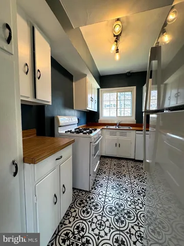 a kitchen with granite countertop a sink a stove a refrigerator and cabinets